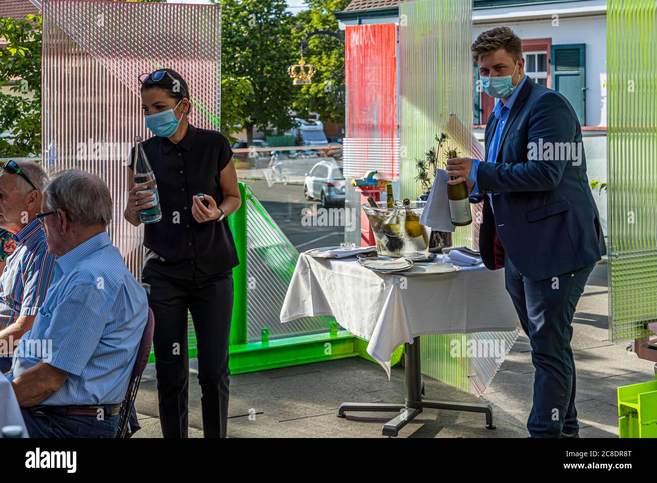 Outside catering with artistically designed partition walls and waiters with protective masks in Hotel Krone in Weil am Rhein, Germany. Service with mouth guard between distance objects by Samuel Treidl Stock Photo