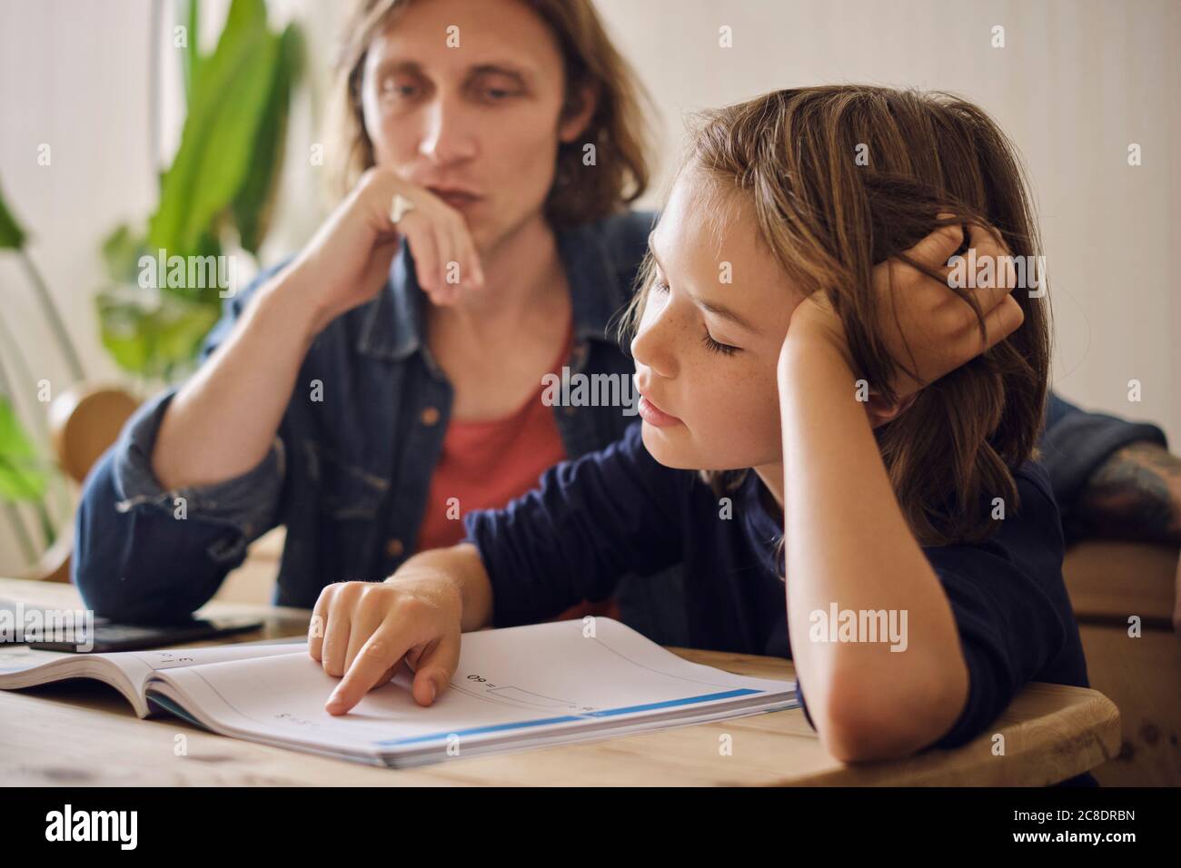 Father assisting son in doing homework at home Stock Photo