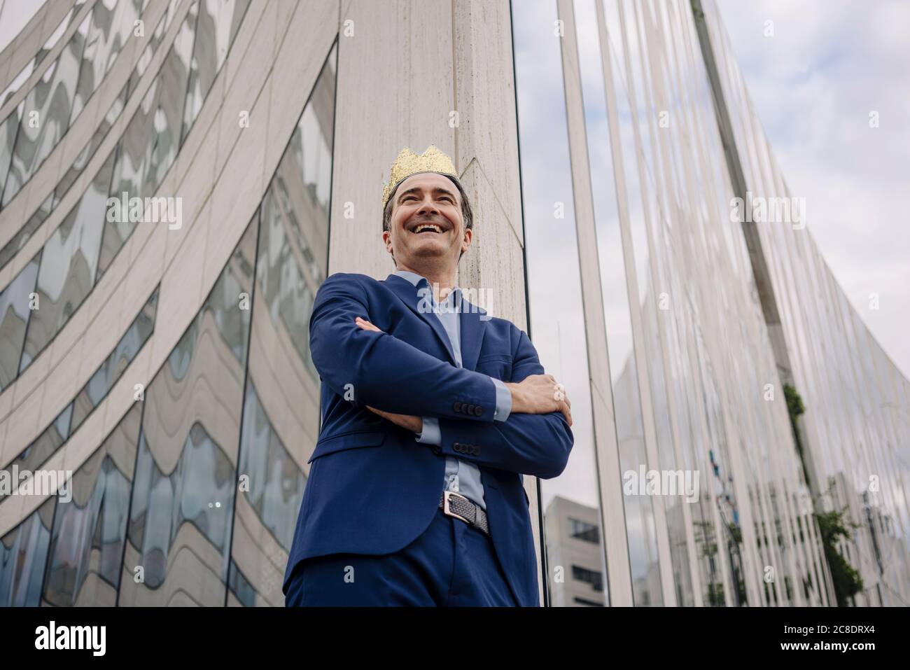 Happy mature businessman wearing a toy crown in the city Stock Photo