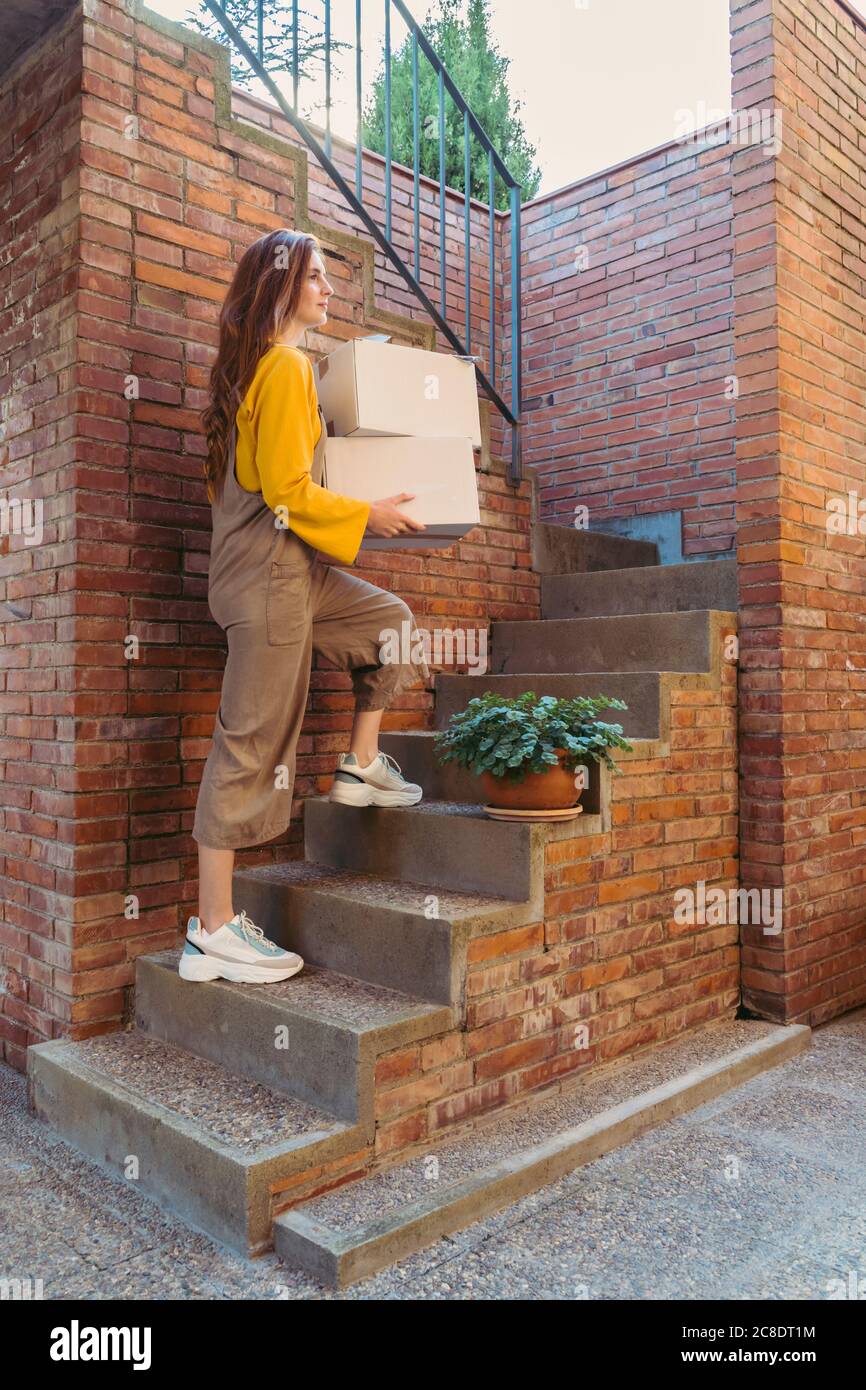 Young woman carrying white boxes while moving up on steps by brick wall Stock Photo Alamy