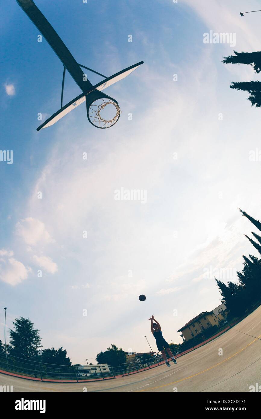 Fish-eye view of teenage girl playing basketball against sky Stock Photo