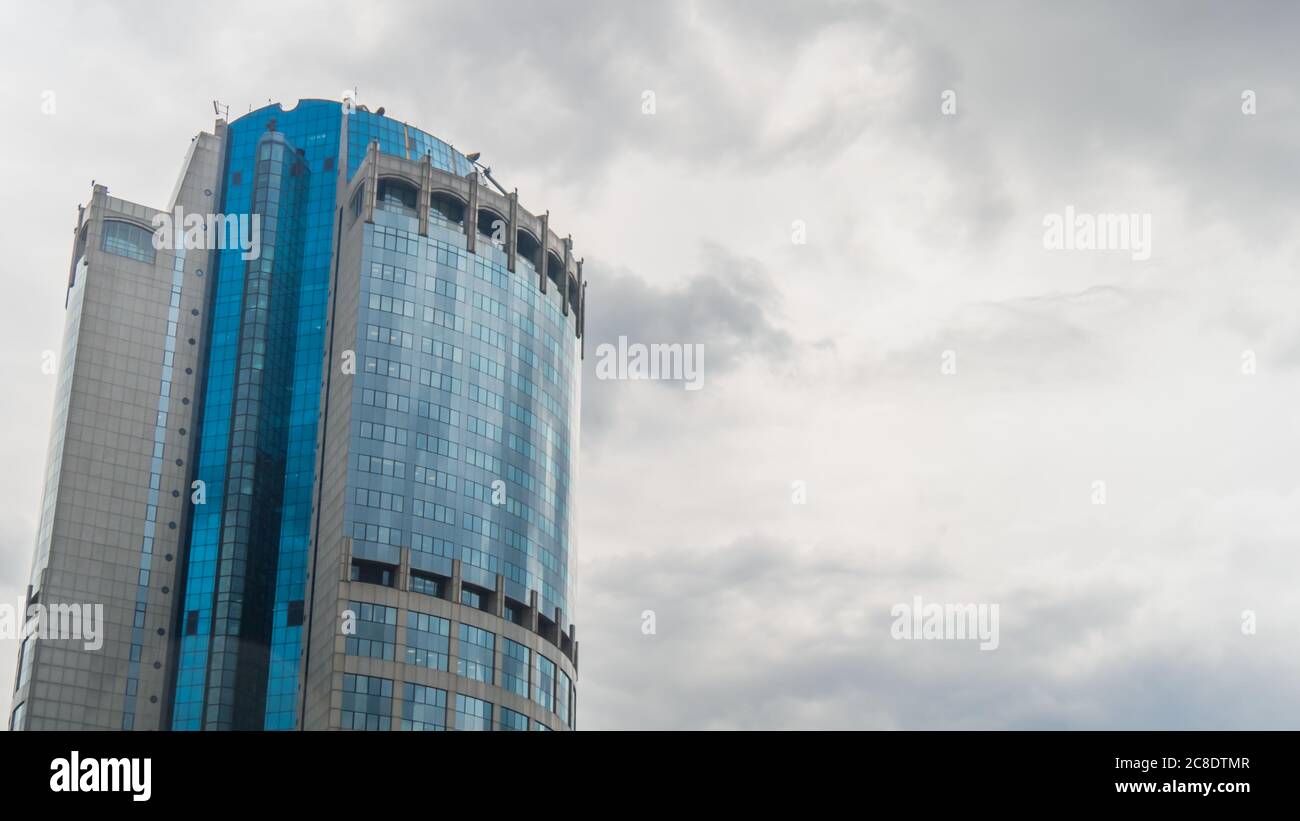 Reflection of white clouds in glass wall of modern tall building, skyscraper. Daylight, overcast. Architecture, corporate, financial, business, urban Stock Photo