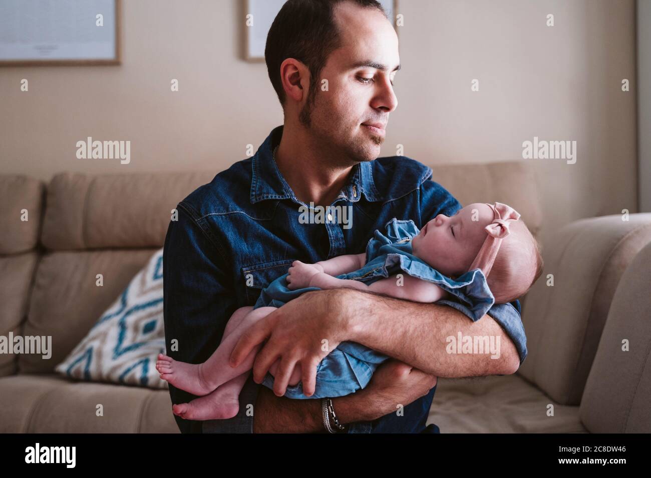 Father carrying sleeping baby girl on sofa at home Stock Photo Alamy