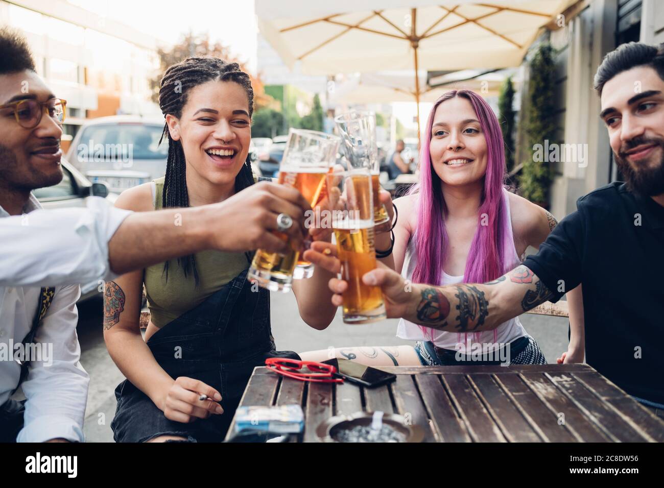Happy friends clinking beer glasses outdoors at a bar Stock Photo