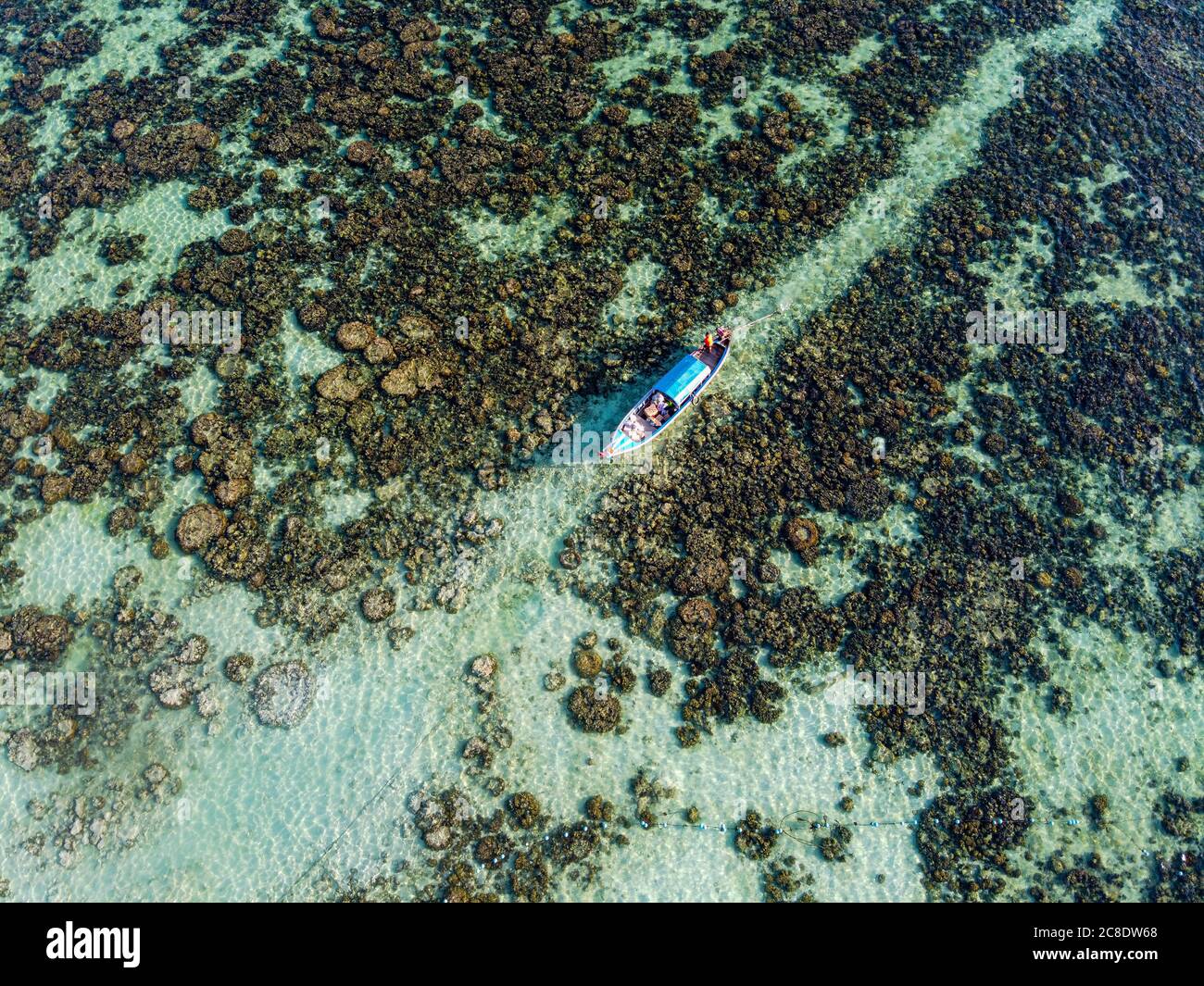 Thailand, Satun Province, Ko Lipe, Aerial view of fishing boat moored at rocky shore Stock Photo