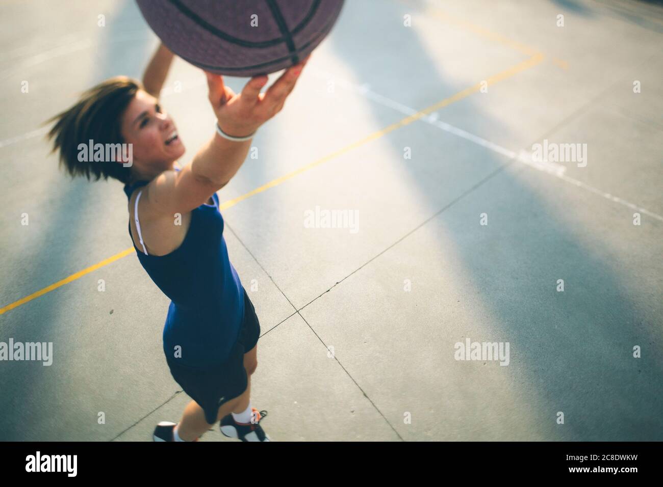 Teenage girl jumping while practicing basketball on court Stock Photo