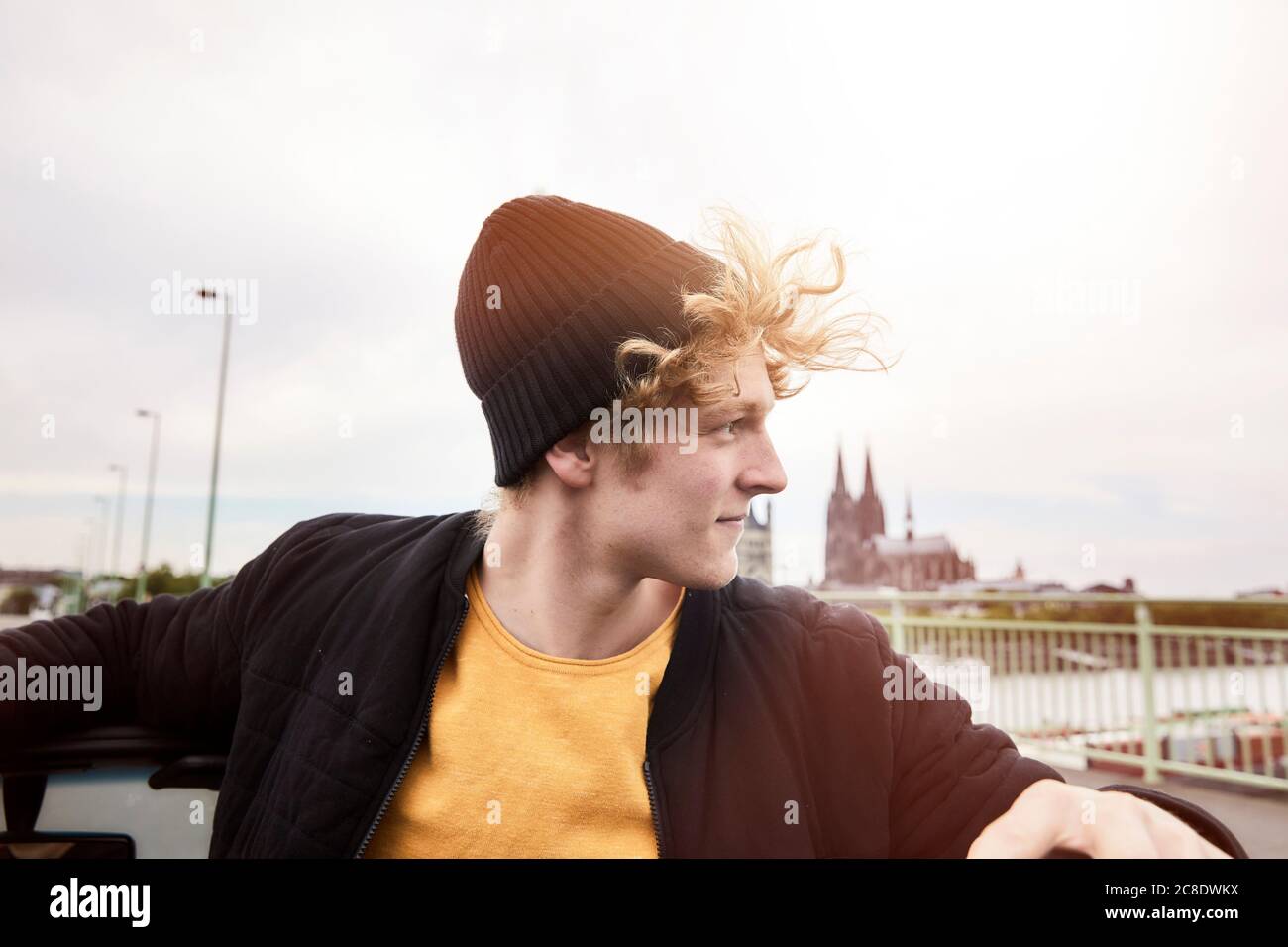 Portrait of young man with blowing hair wearing black cap, Cologne, Germany Stock Photo