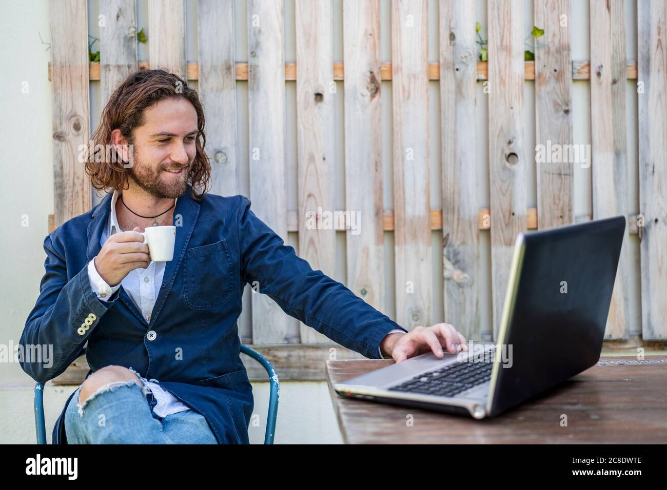 Handsome young businessman drinking espresso while using laptop at cafe Stock Photo