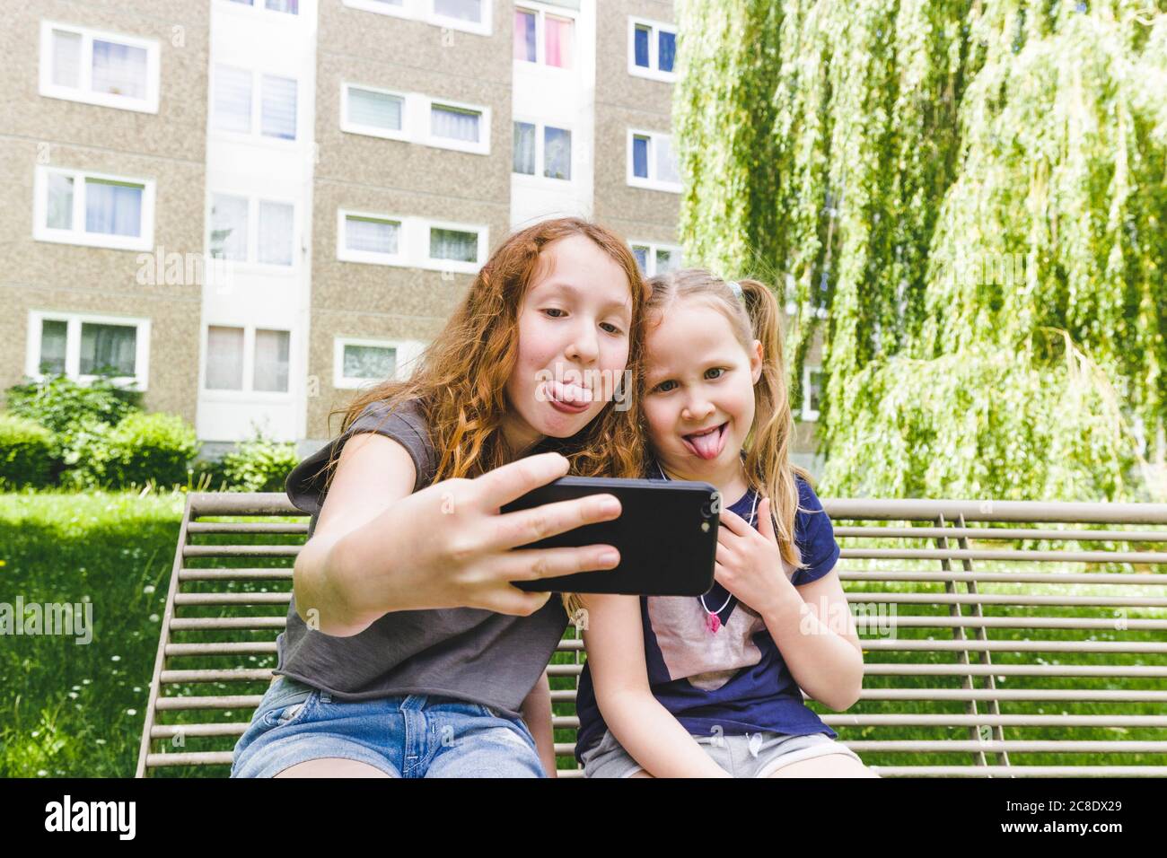 Sisters taking selfie while sticking out tongues at park Stock Photo
