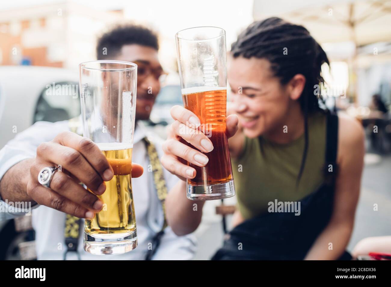 Happy young couple clinking beer glasses outdoors at a bar Stock Photo