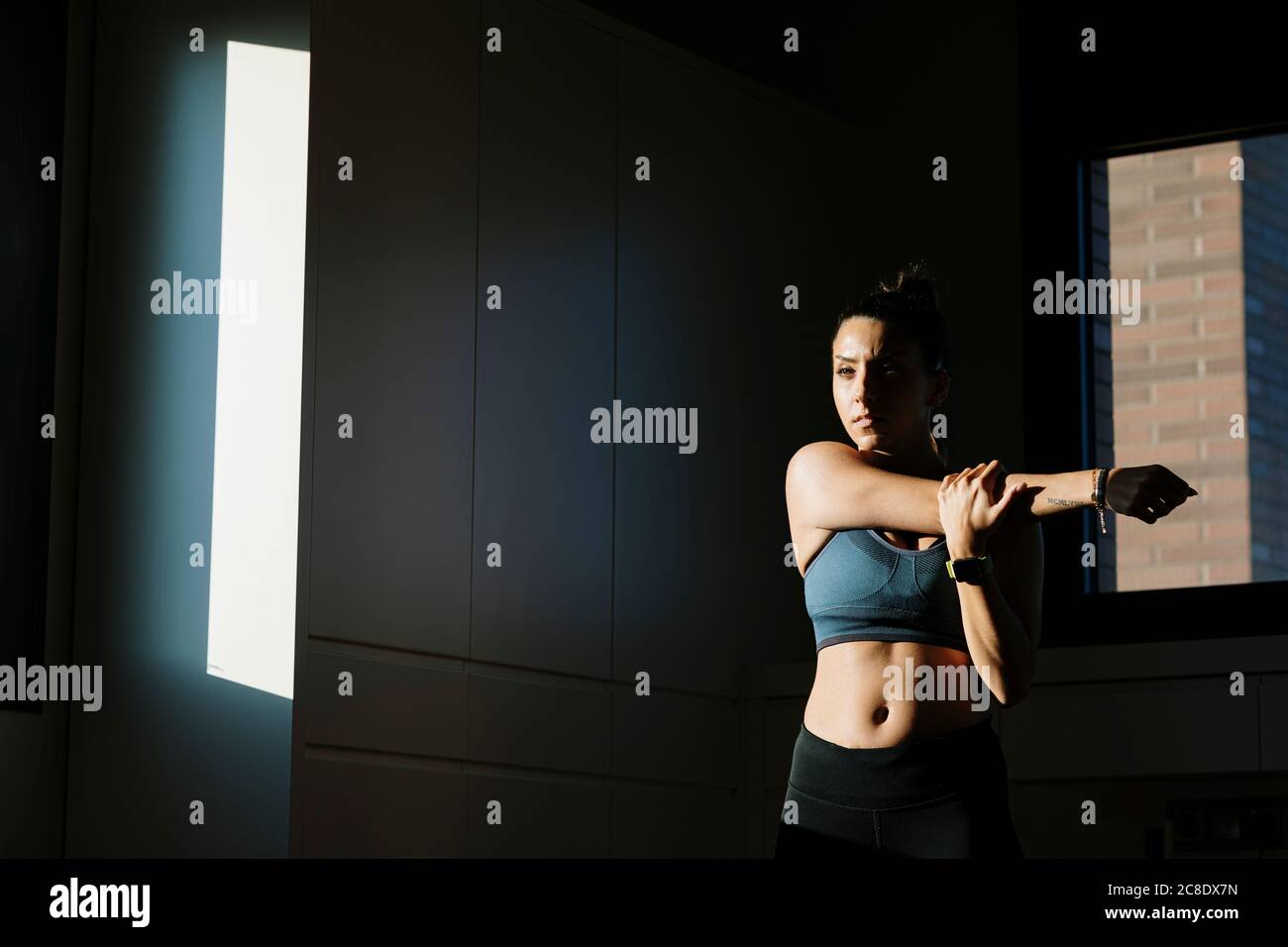 Young woman stretching her arm at home Stock Photo