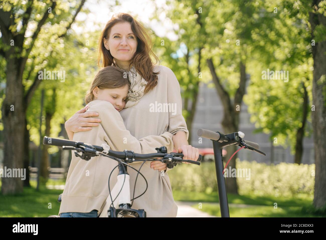 Mother and daughter embracing while spending leisure time in city park Stock Photo