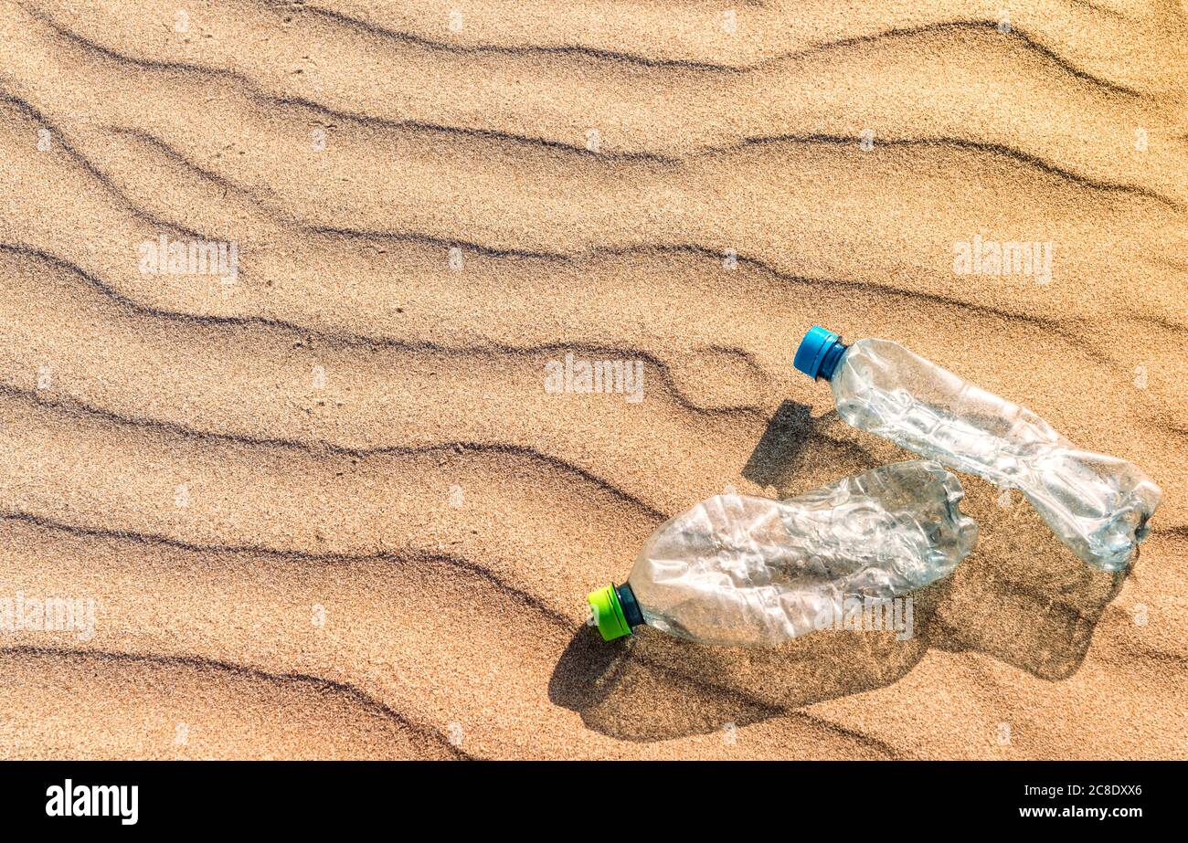 Plastic bottles lying on rippled beach sand Stock Photo