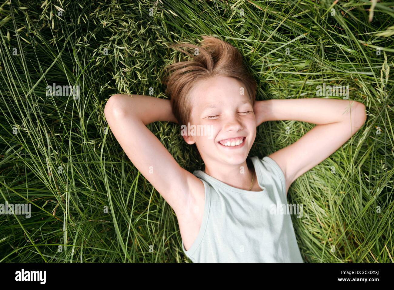 Portrait of happy boy with eyes closed lying on a meadow in summer Stock Photo