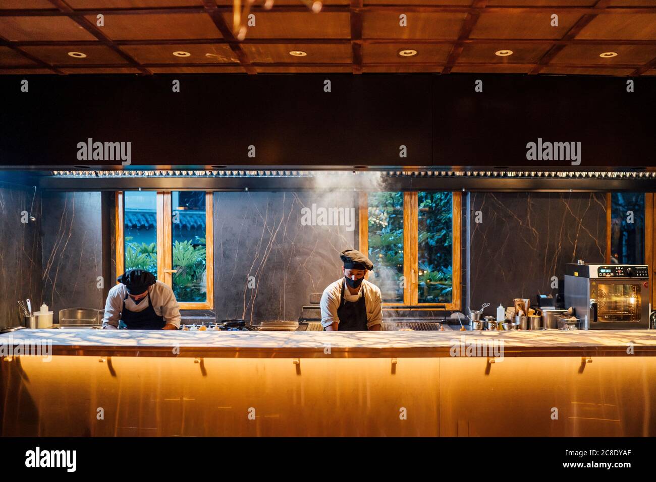 Chefs wearing protective face masks working in restaurant kitchen Stock Photo Alamy
