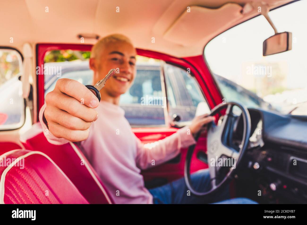 Happy teenage boy sitting in vintage car showing key Stock Photo