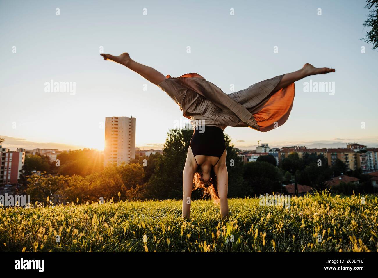 Young woman performing handstand at city park during sunset Stock Photo