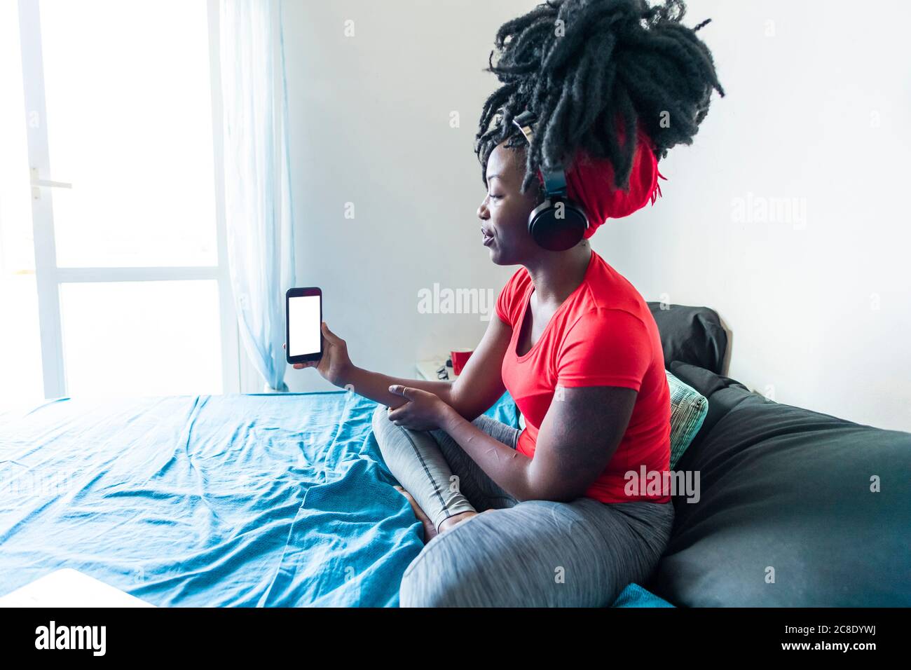Young woman with headphones using smartphone for video call Stock Photo