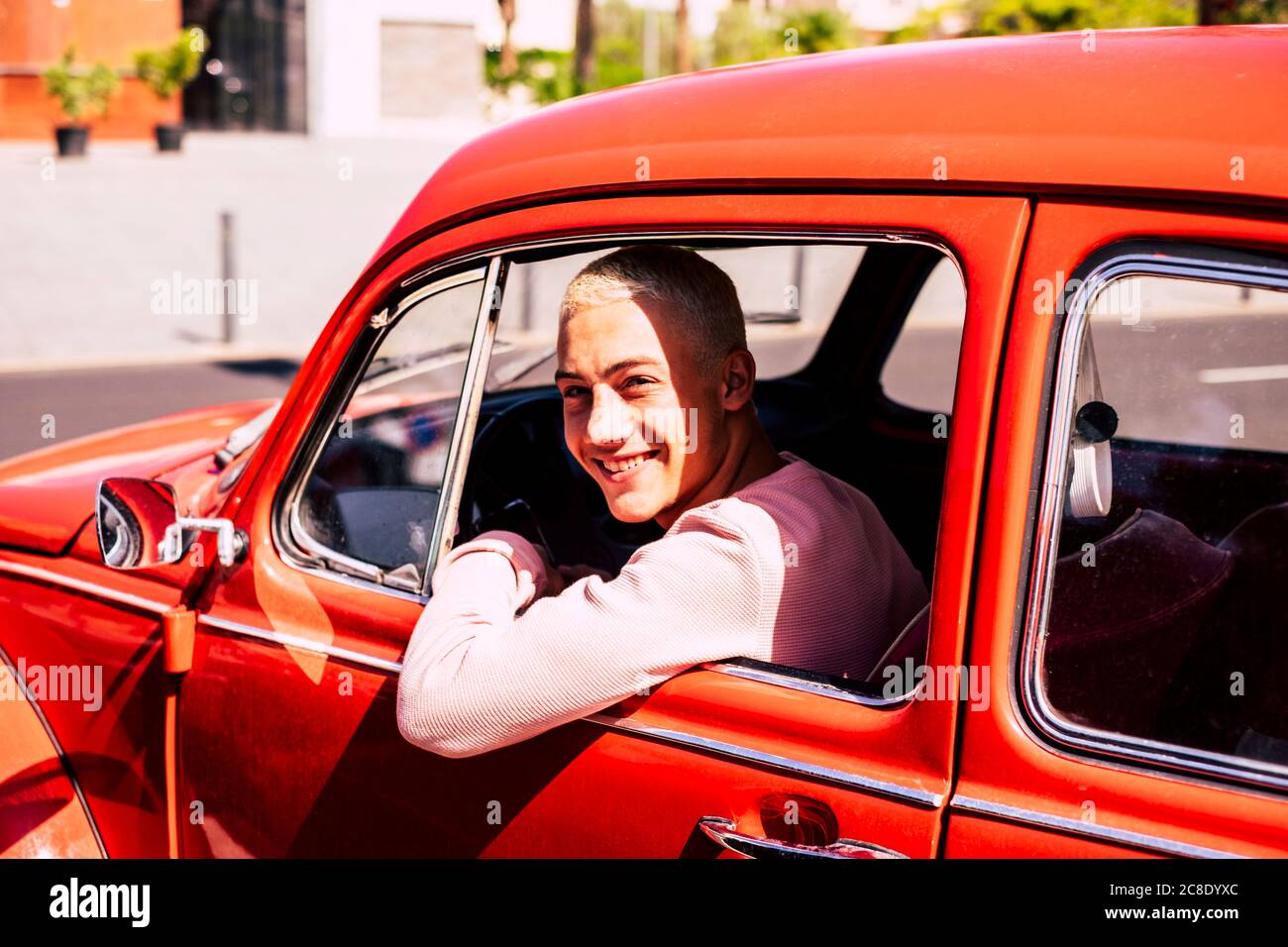 Portrait of happy teenage boy sitting in vintage car looking out of window Stock Photo