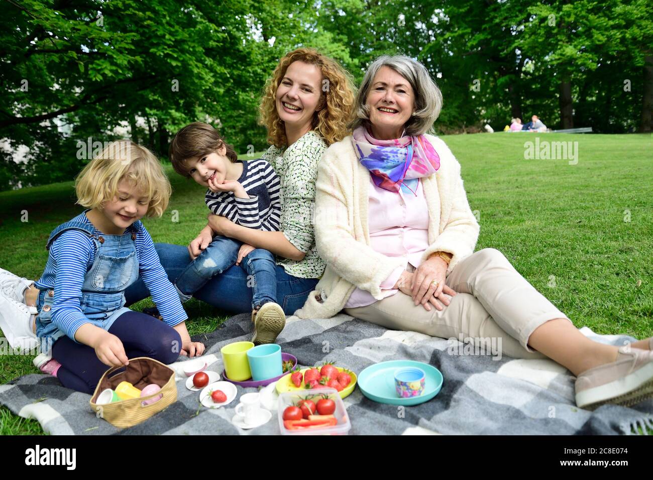 Happy three generation family enjoying picnic at public park Stock Photo