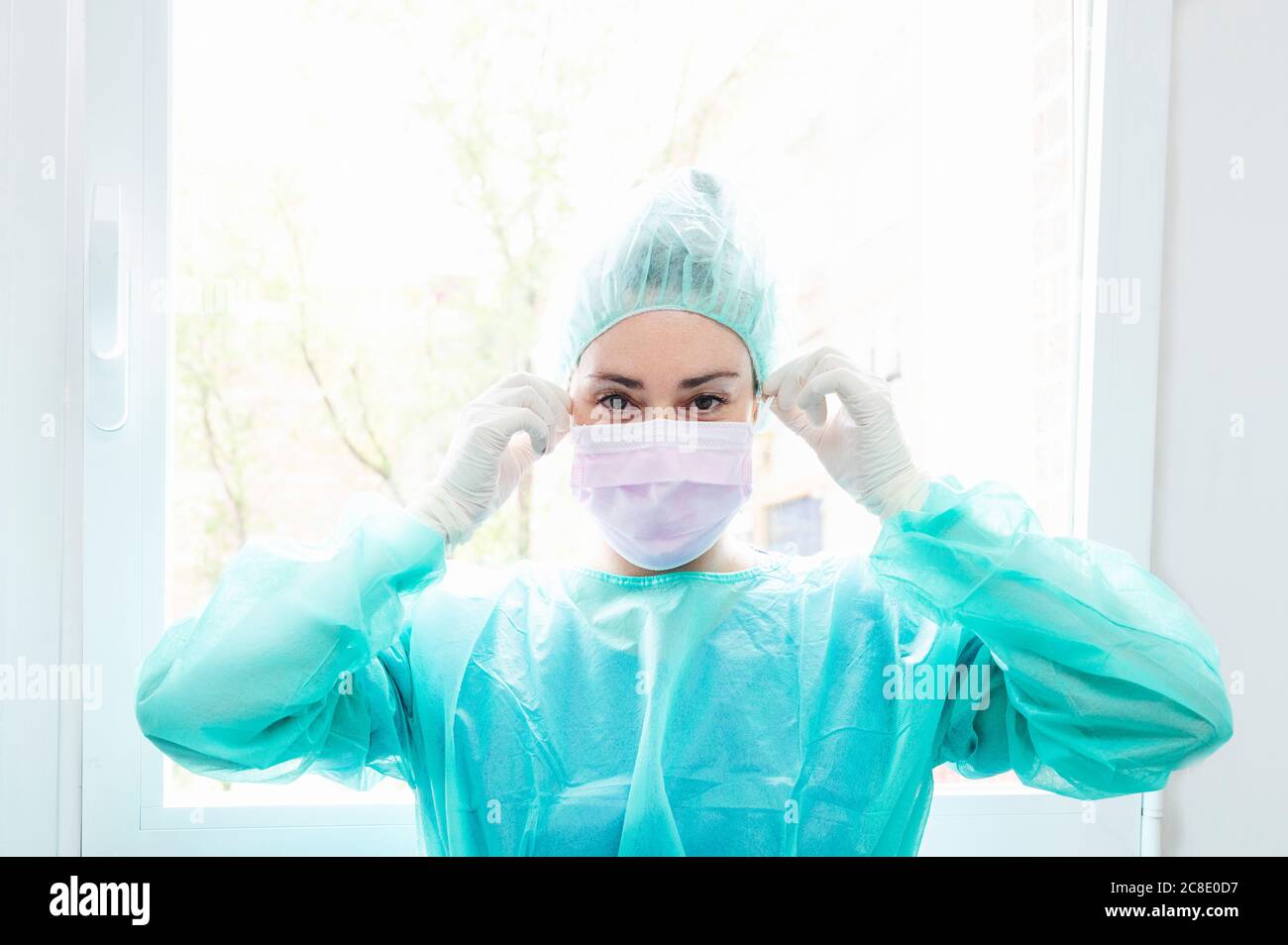 Close up Of Nurse Wearing Surgical Mask Against Window In Hospital close-up-of-nurse-wearing-surgical-mask-against-window-in-hospital