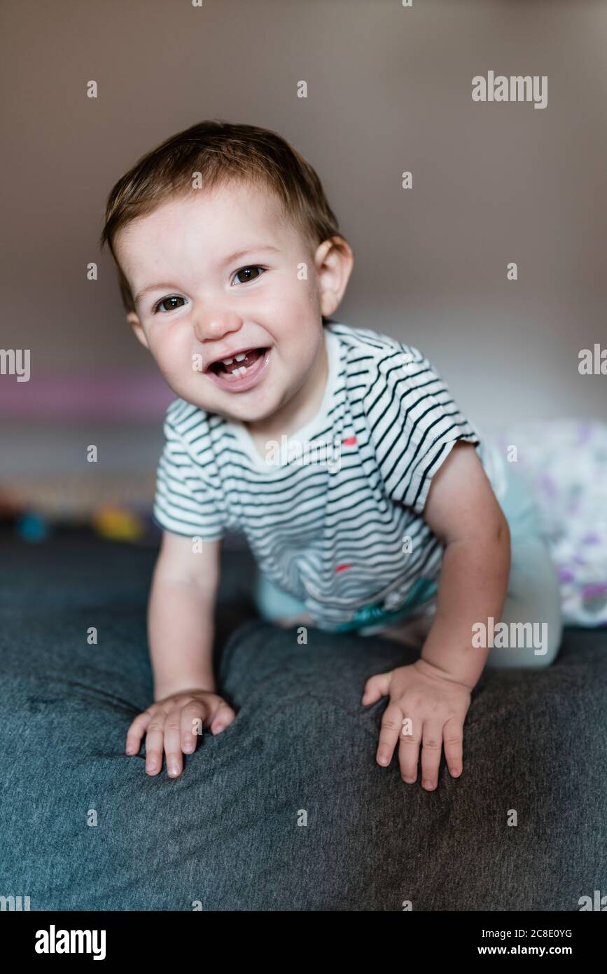 Portrait of happy baby girl crawling on bed Stock Photo