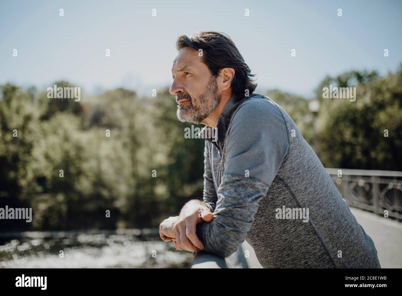 Thoughtful man looking away while standing on footbridge against clear sky Stock Photo