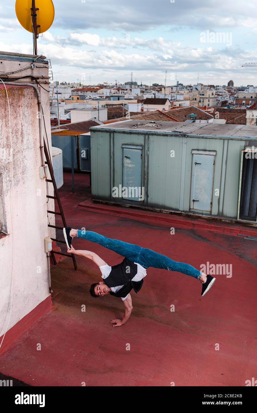 Young man breakdancing on building terrace in city Stock Photo
