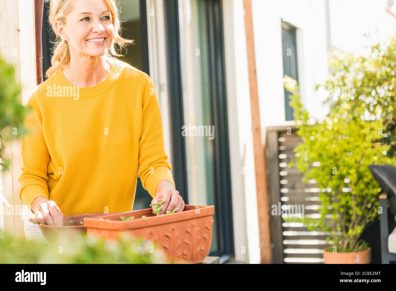Portrait of smiling mature woman gardening on terrace Stock Photo