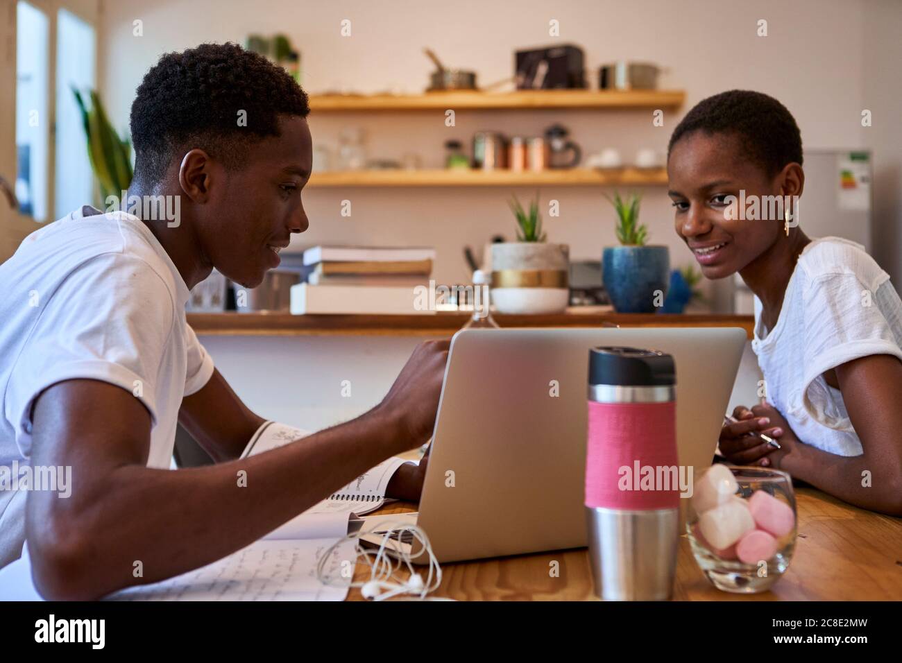 Smiling couple discussing doubts over laptop while studying at home Stock Photo