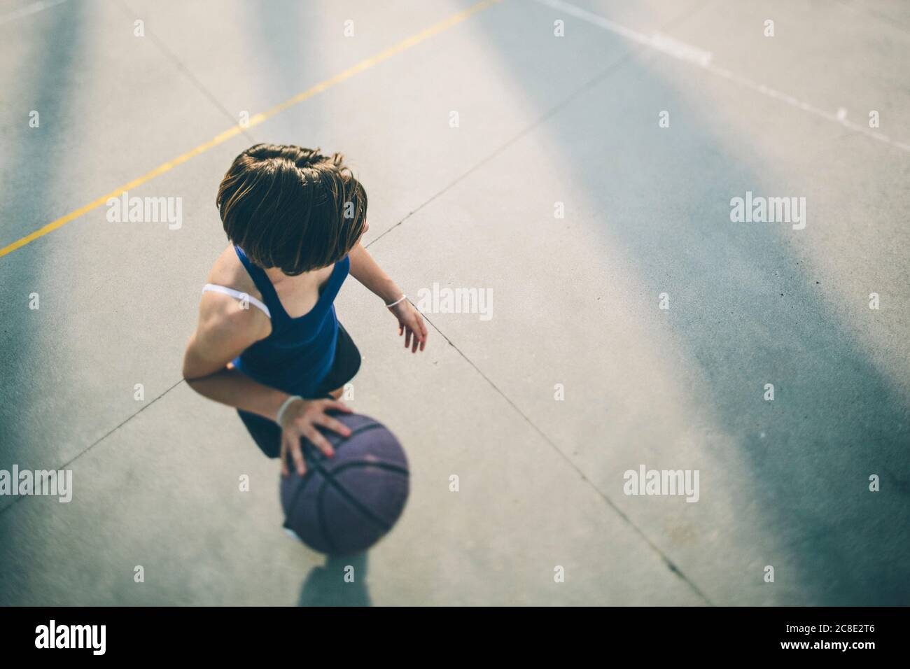 Teenage athlete practicing dribbling basketball on court Stock Photo