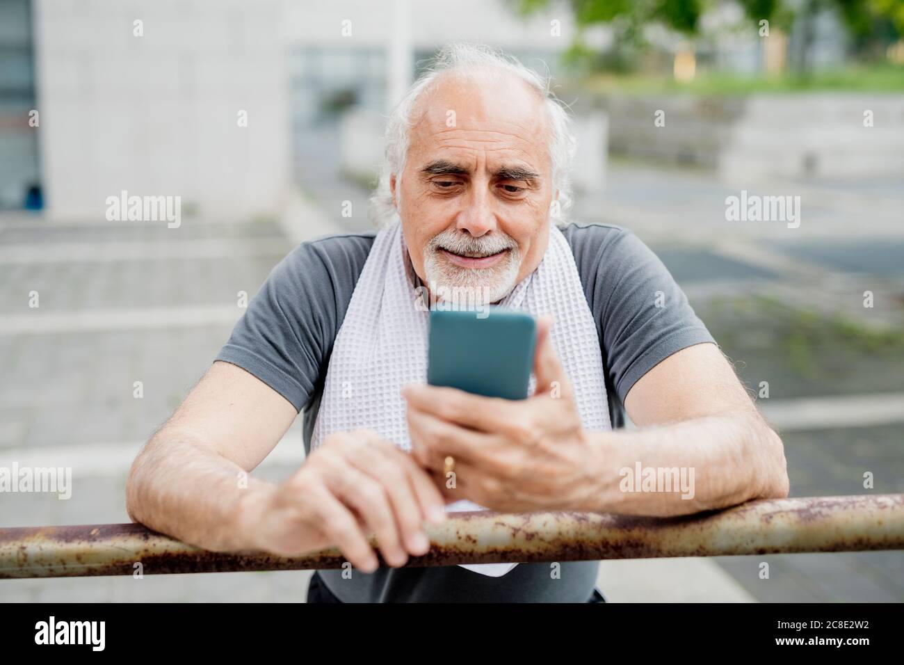 Close-up of senior man using smart phone while standing by railing Stock Photo