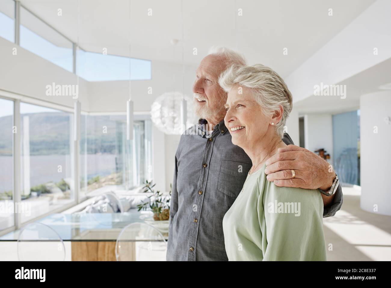 Happy senior couple in luxury beach house looking out of window Stock Photo