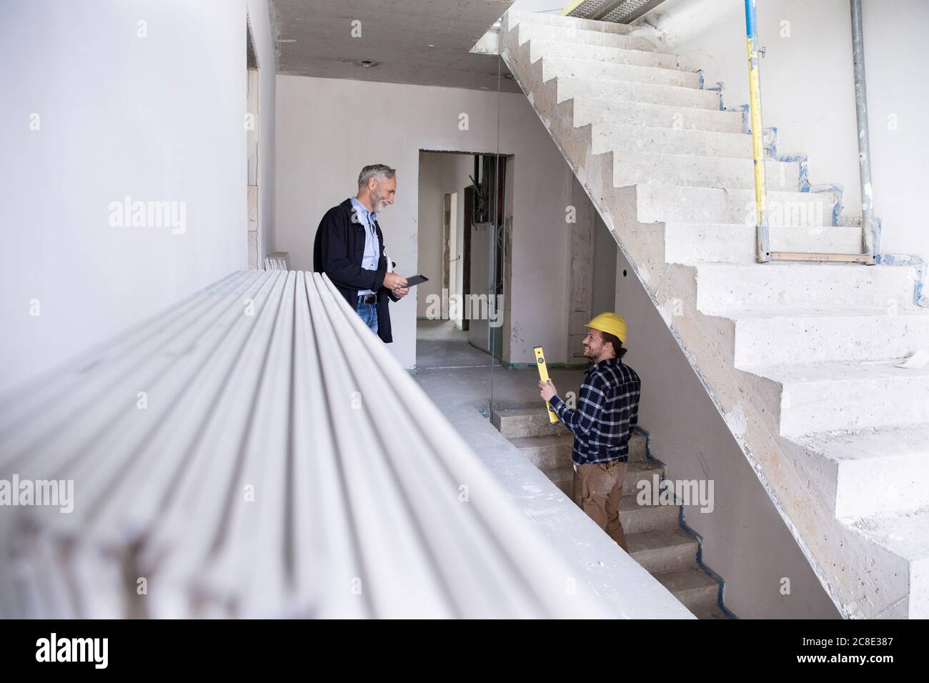 Architect and construction worker discussing while standing in constructing house Stock Photo