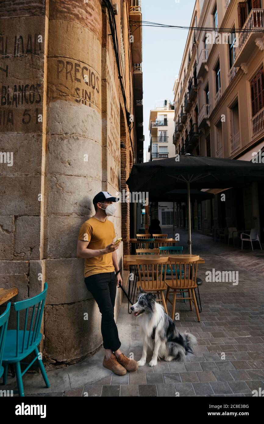 Man wearing protective mask waiting with his dog in the city Stock Photo