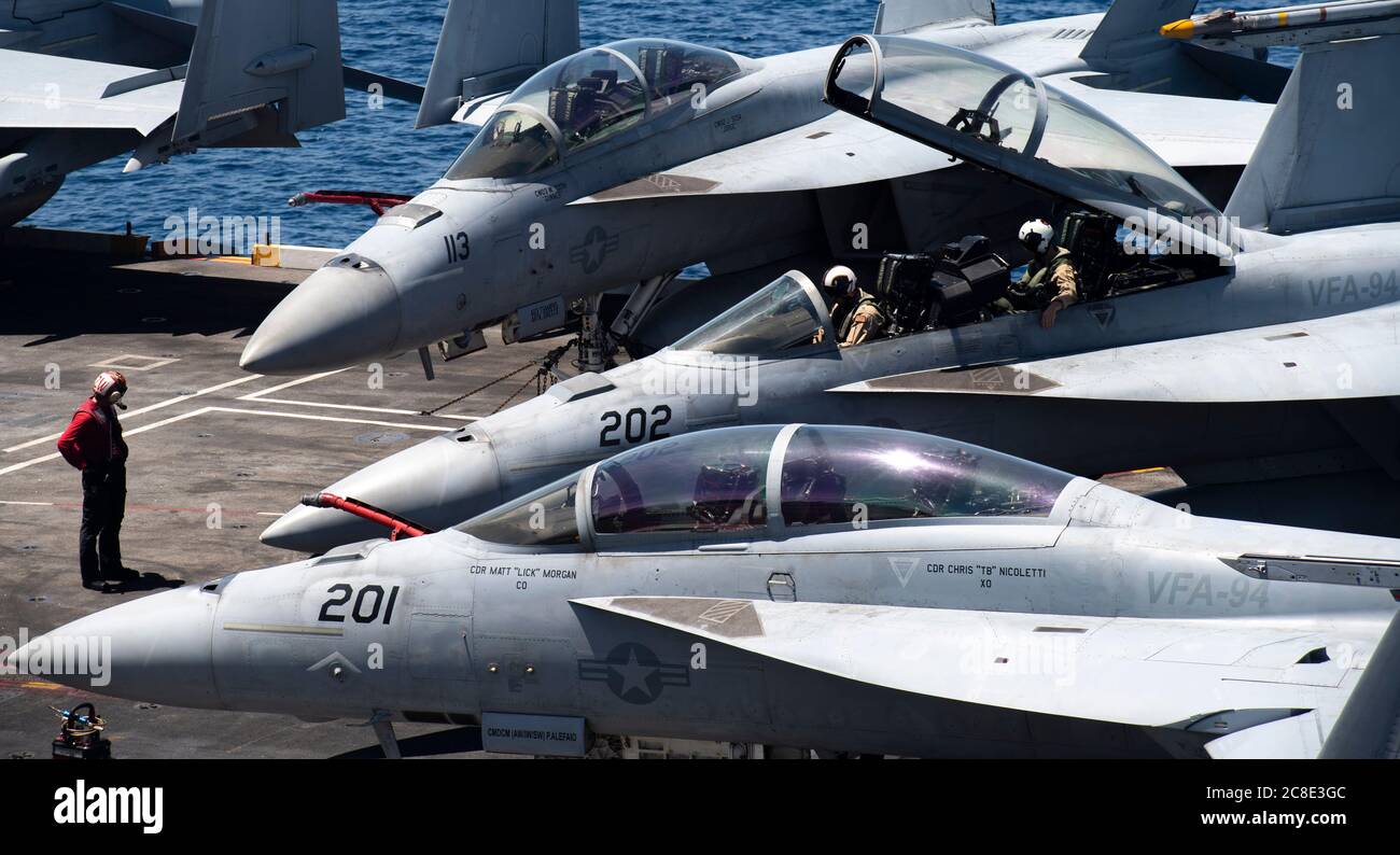 A U.S. Navy flight handler prepares to direct a F/A-18E Super Hornet fighter aircraft, on the flight deck of the Nimitz-class nuclear aircraft carrier USS Nimitz underway transiting the Surigao Strait July 14, 2020 in the Philippine Sea. Stock Photo
