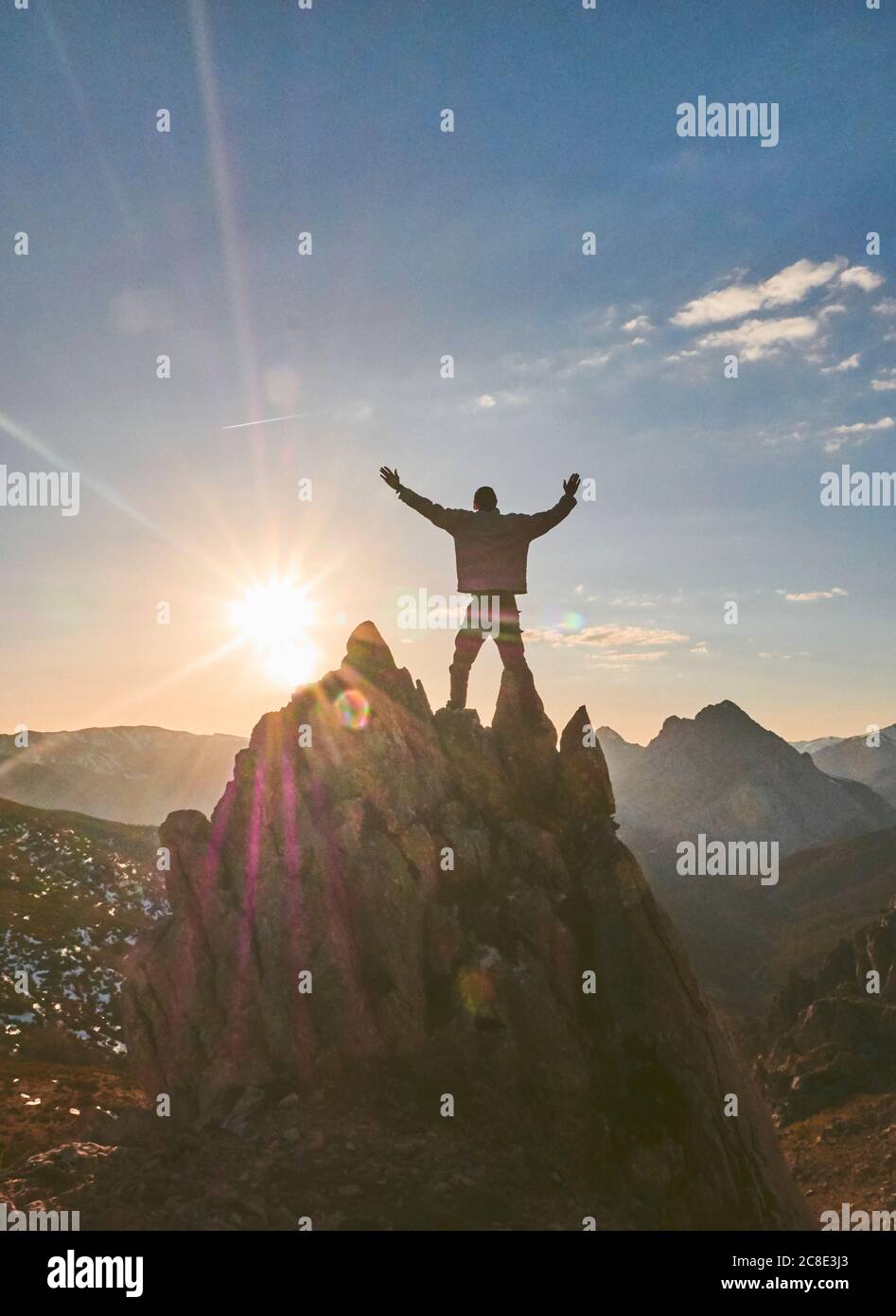 Silhouette male hiker standing with arms outstretched on mountain during sunset, Leon, Spain Stock Photo