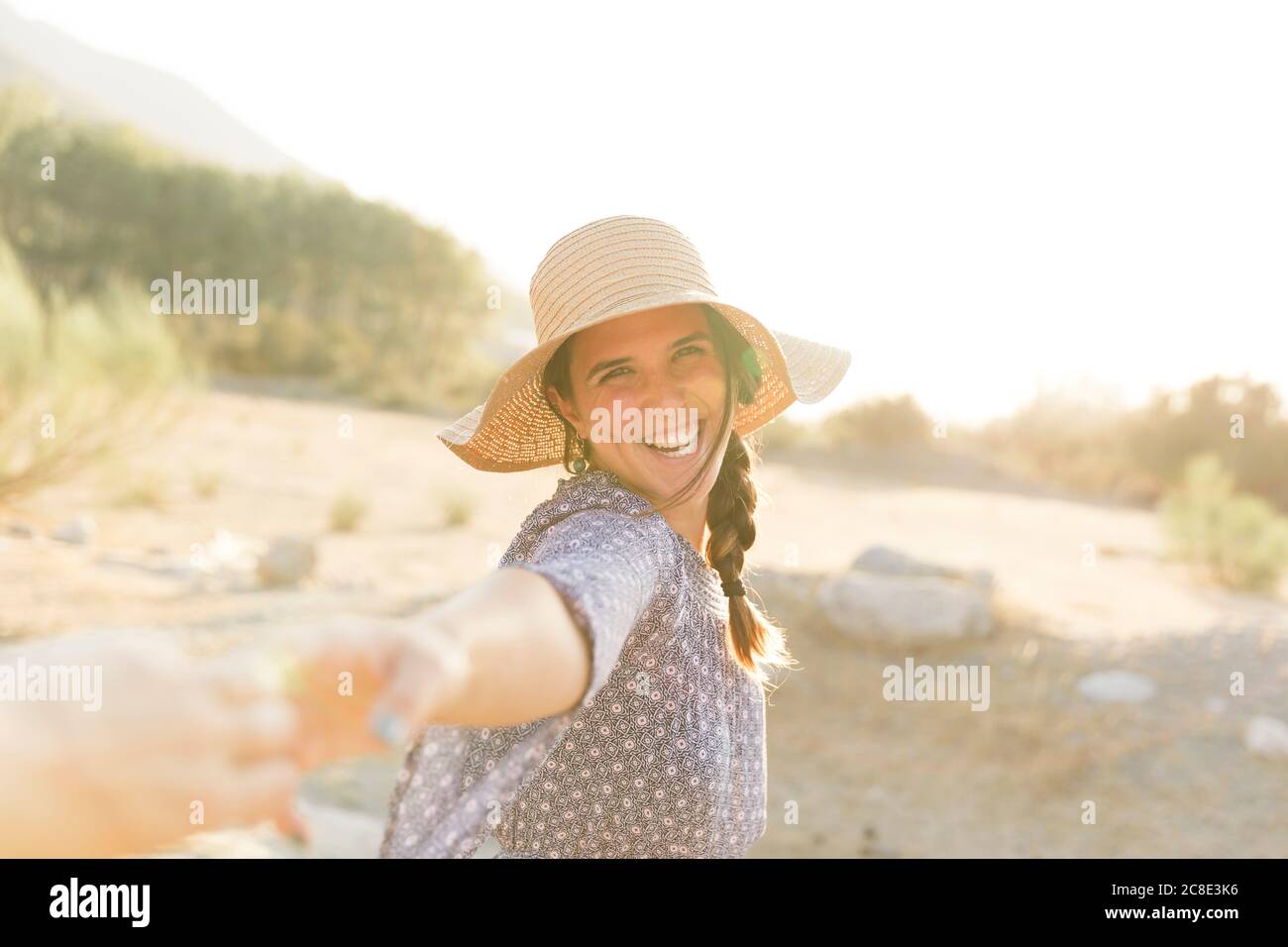 Cheerful young woman wearing sun hat during sunny day Stock Photo
