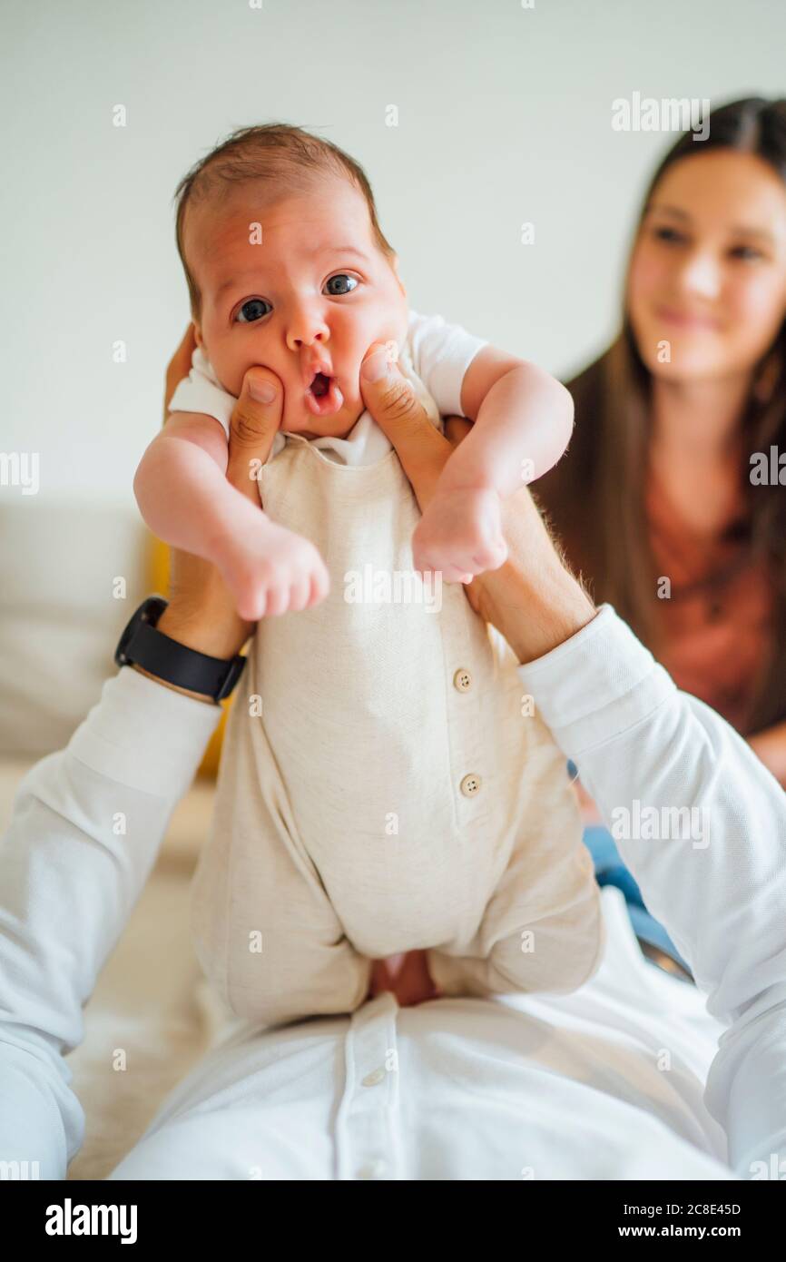 Cute baby boy being carried by father with mother in background in
