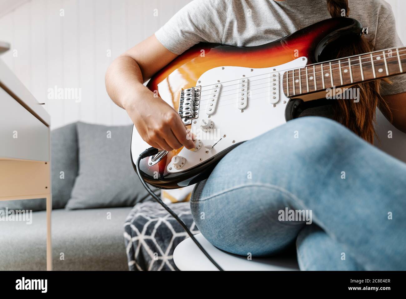 Woman adjusting knobs on electric guitar at home Stock Photo Alamy