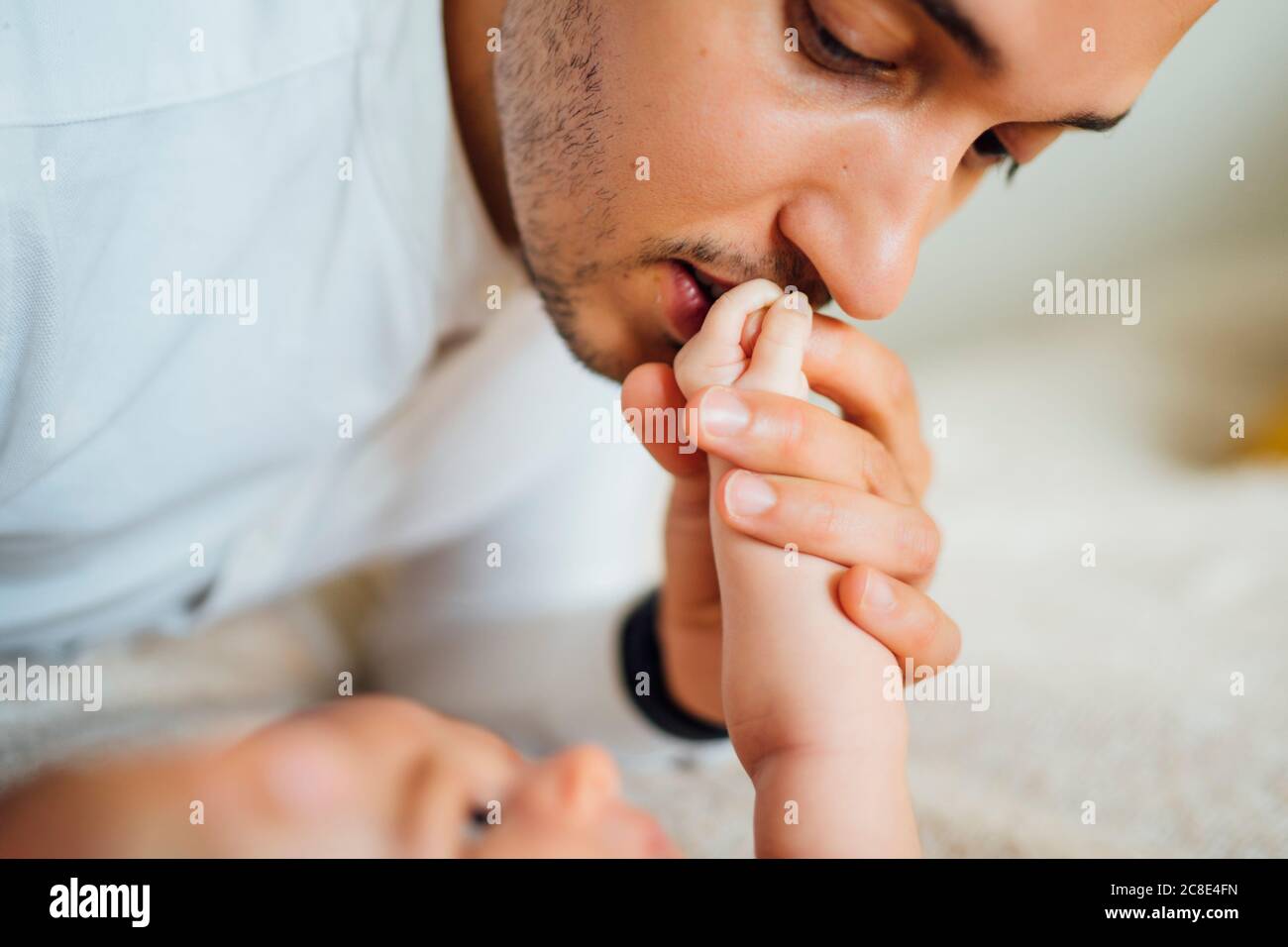 Father kissing baby boy's hand at home Stock Photo