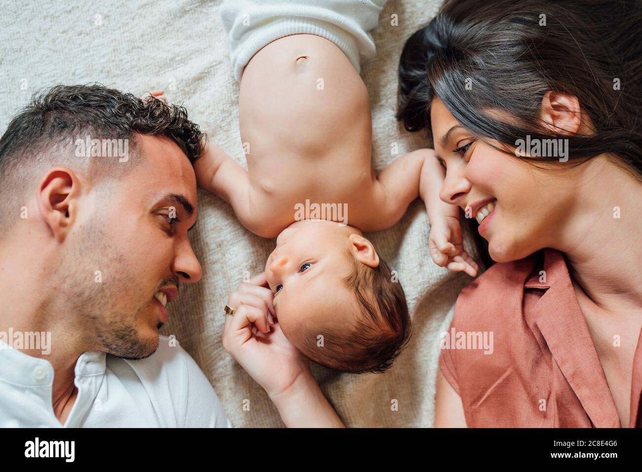 Loving parents lying with baby boy in bedroom at home Stock Photo