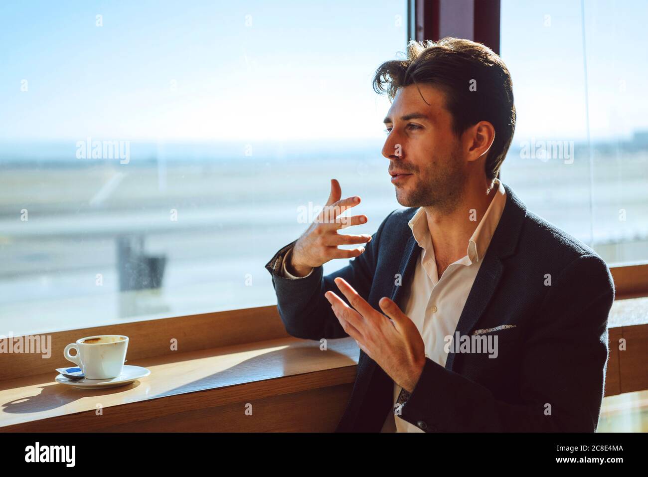 Thoughtful businessman gesturing at airport cafe Stock Photo