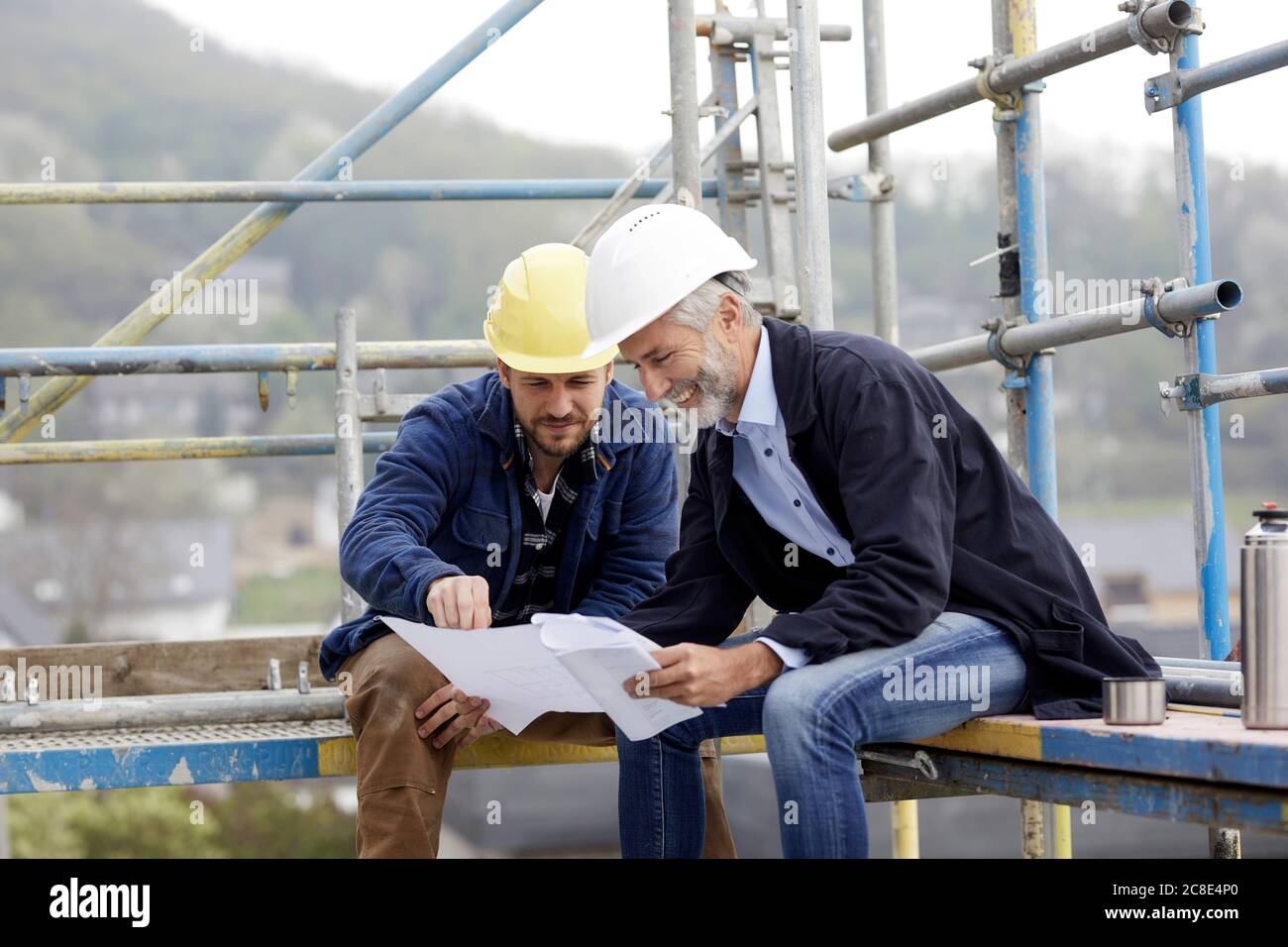 Architect and worker discussing building plan on scaffolding on a construction site Stock Photo
