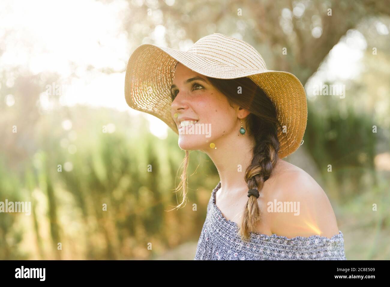 Thoughtful young woman wearing sun hat during sunny day Stock Photo