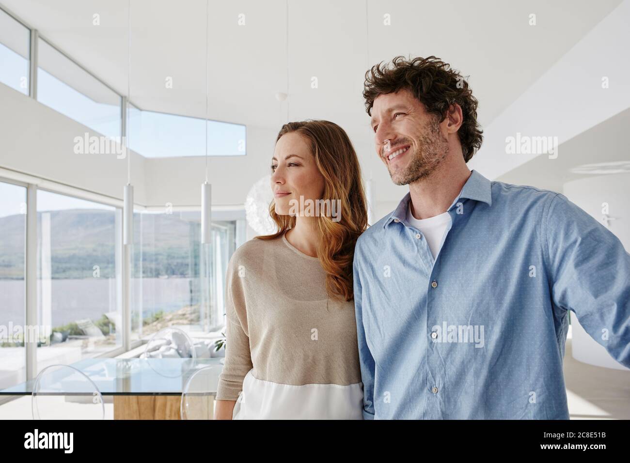 Couple in luxury beach house looking out of window Stock Photo