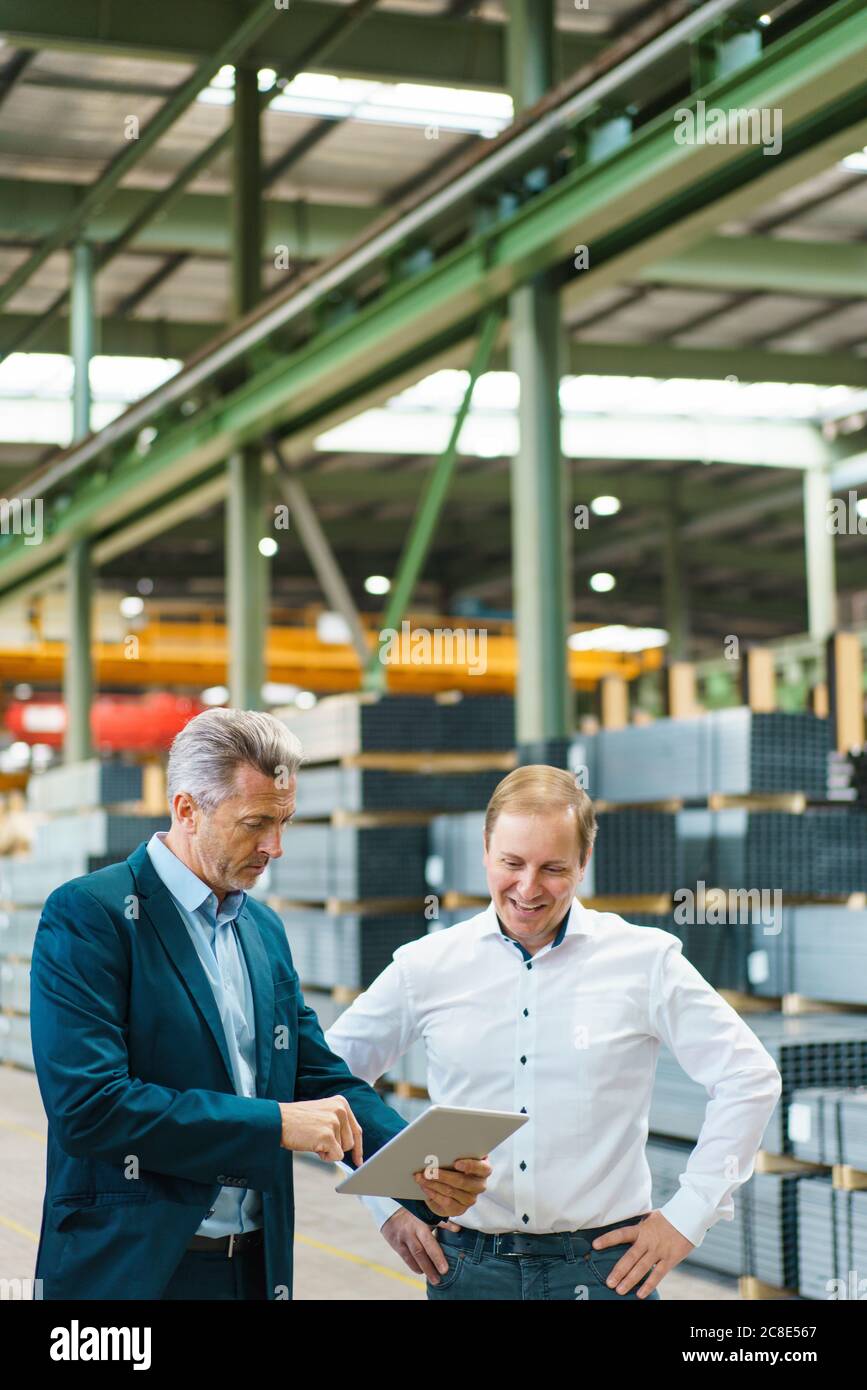 Two businessmen using tablet in a factory Stock Photo