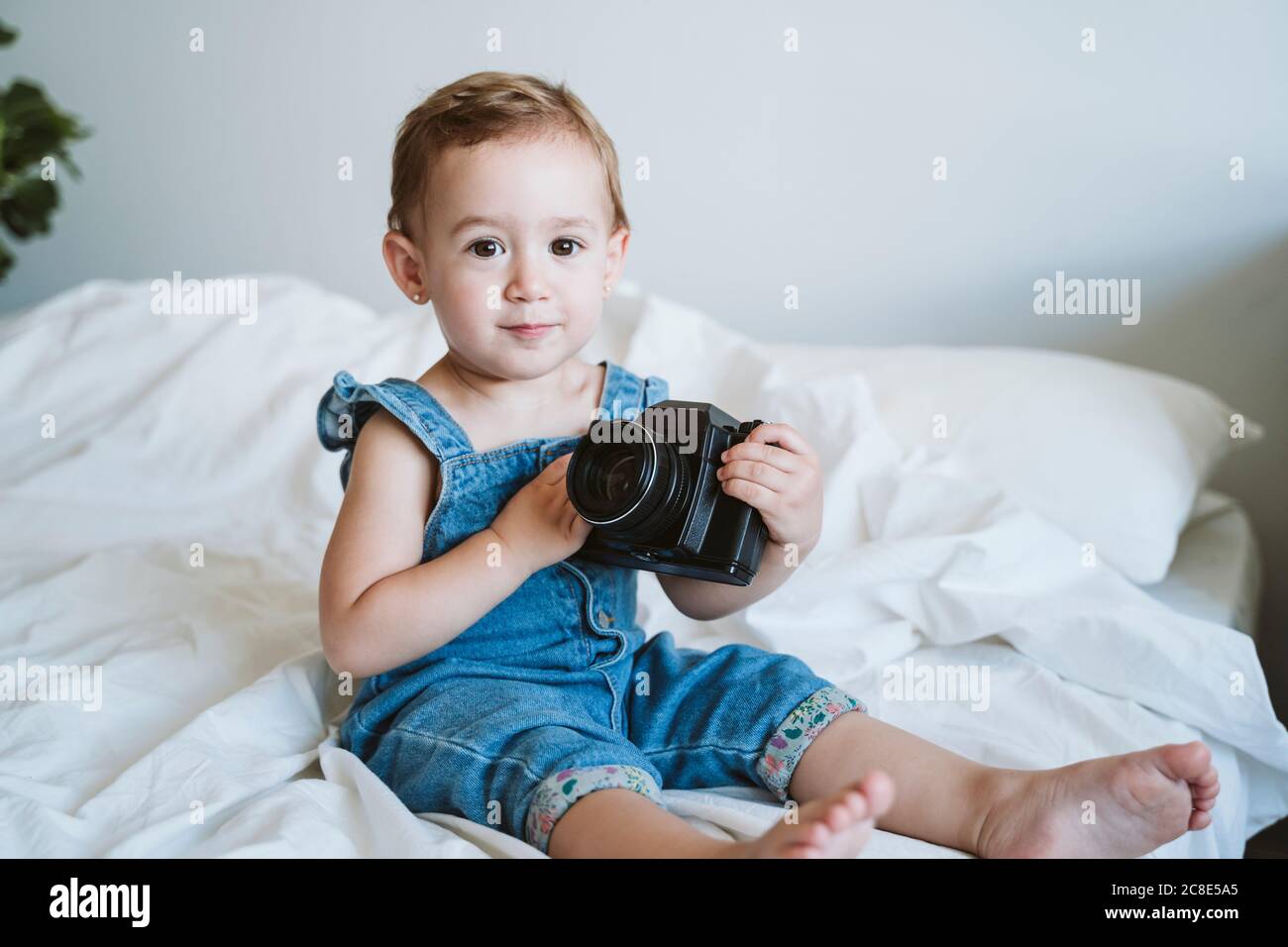 Baby girl holding camera at home Stock Photo - Alamy