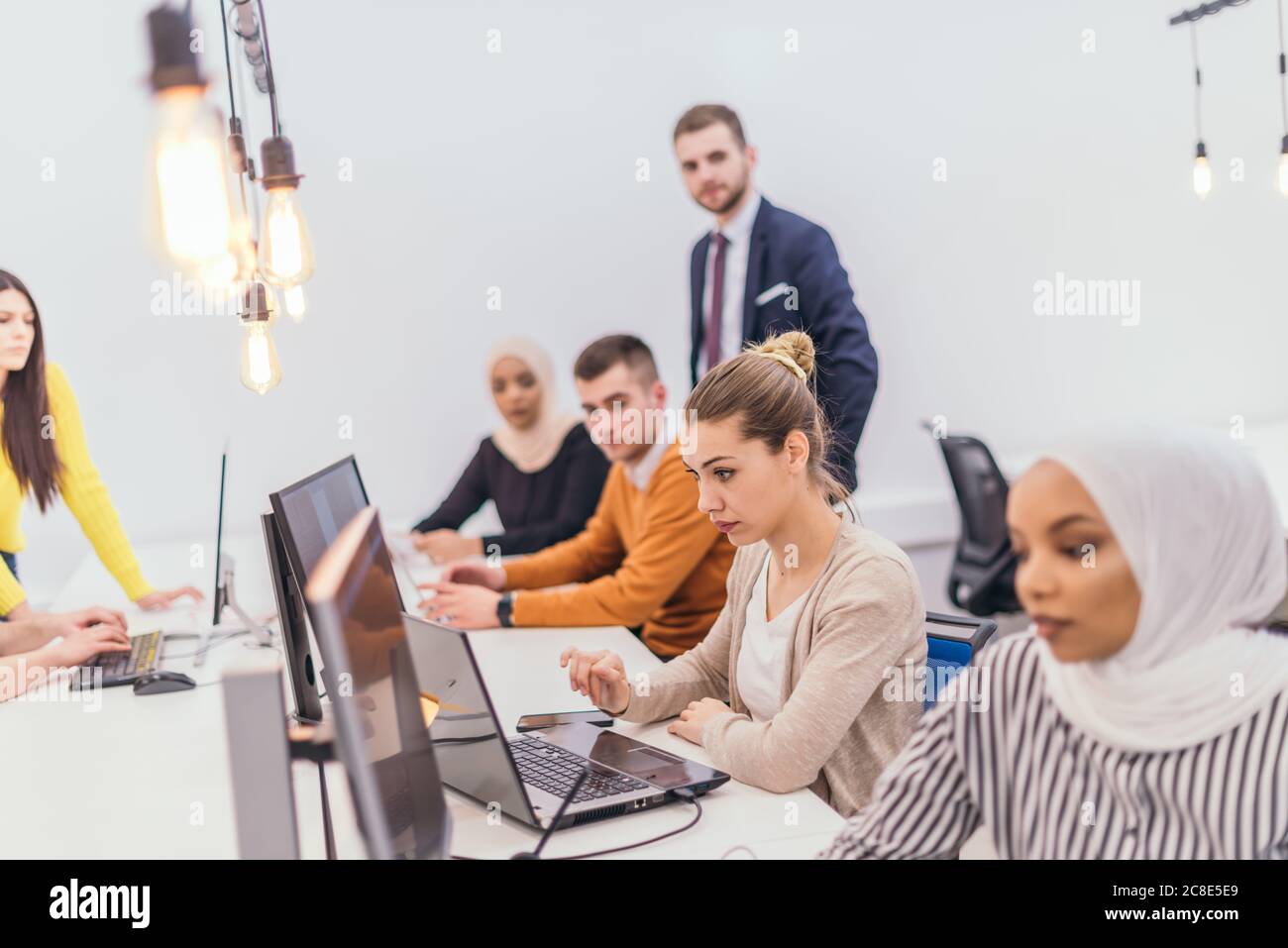 Group of multi-ethnic colleagues working on desktop computers in a ...