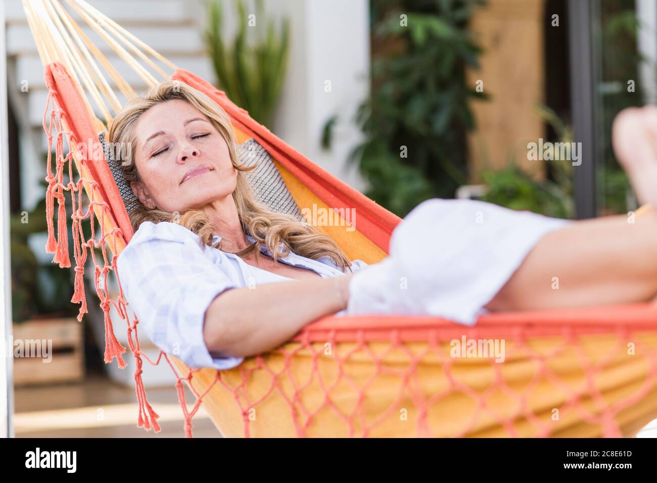 Portrait of mature woman with eyes closed relaxing in hammock on ...